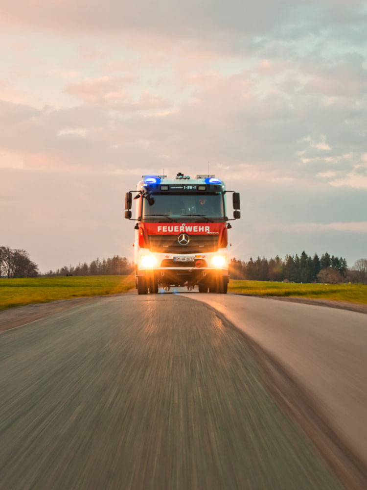 Feuerwehrauto auf Landstraße bei Sonnenuntergang
