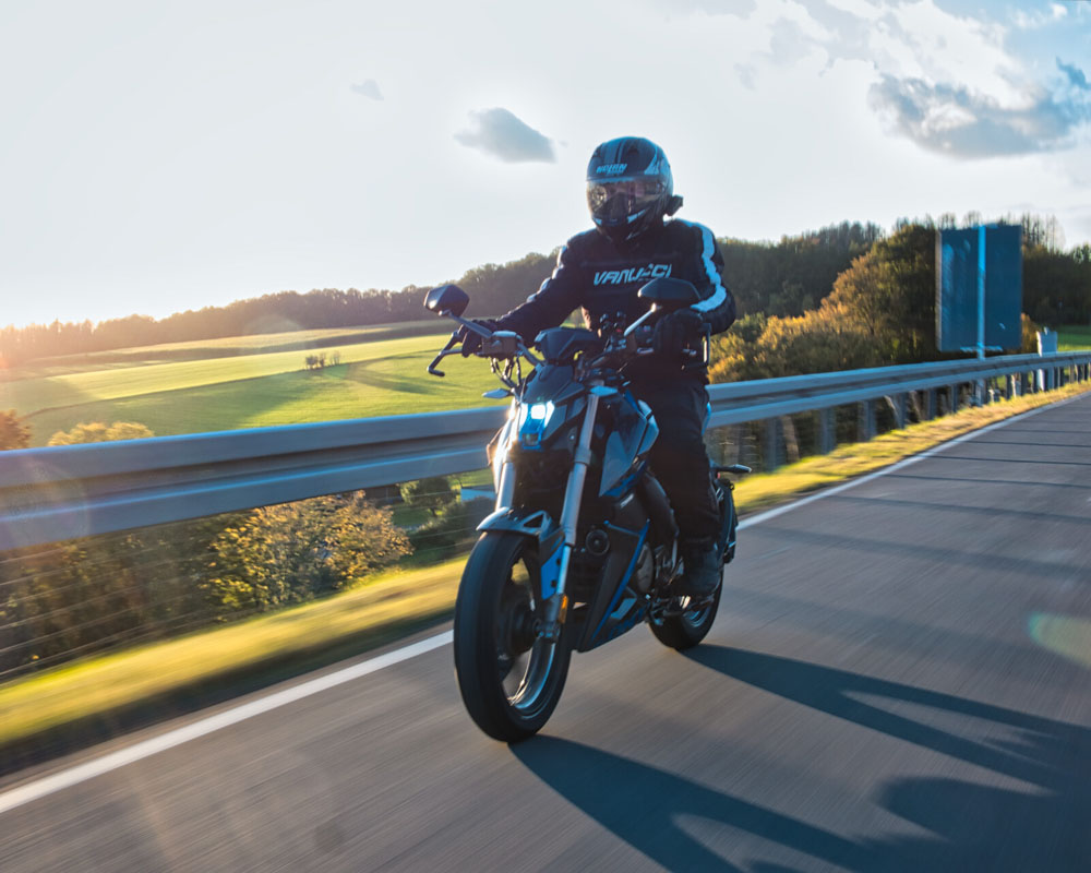 Motorradfahrer auf kurviger Straße bei Abendsonne