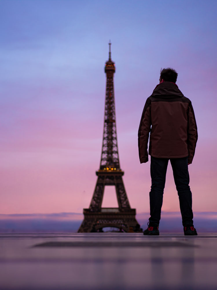 Person vor dem Eiffelturm bei Sonnenuntergang in Paris