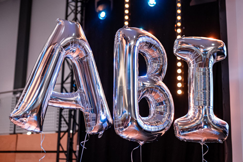 Silberne Folienballons formen das Wort ABI als Dekoration für eine Abiturfeier.